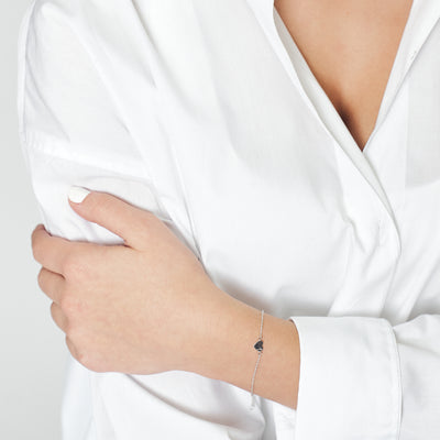 Kvinna i vit skjorta som bär armband med hjärta