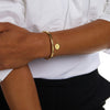 arm framför vit skjorta och svarta byxor med två guldarmband