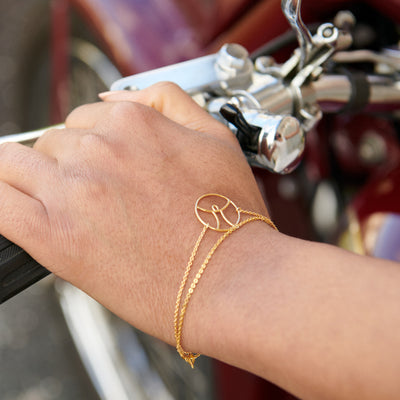 Hand som håller i styret på en klassisk motorcykel, armband med ängel i fokus