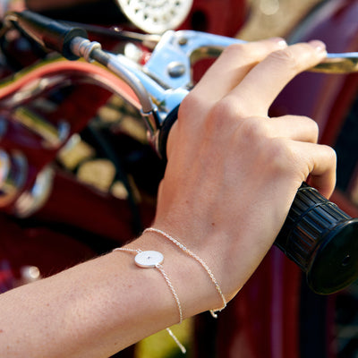 the mustard seed silverarmband påp en hand som hålller i styret på en klassisk motorcykel
